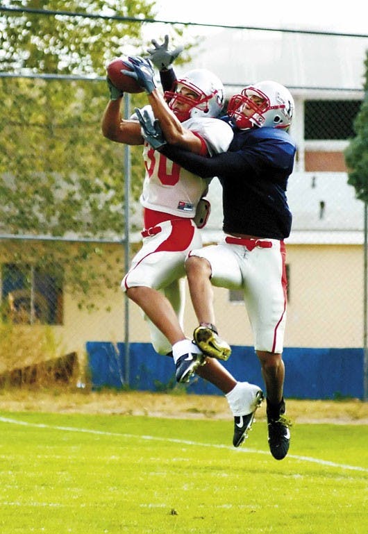 Lobo freshman cornerback Ian Clark, left, intercepts a pass during a drill at the UNM football practice field on Tuesday.