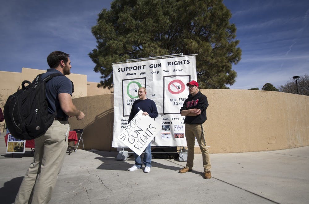 Ryan Boyle and Josh Cde Baca, members of the UNM Young Americans for Freedom  group, speak with a student about gun rights on Thursday. UNM Young Americans for Freedom rallied outside of Zimmerman Library while offering flyers that included gun facts and plastic squirt guns. 