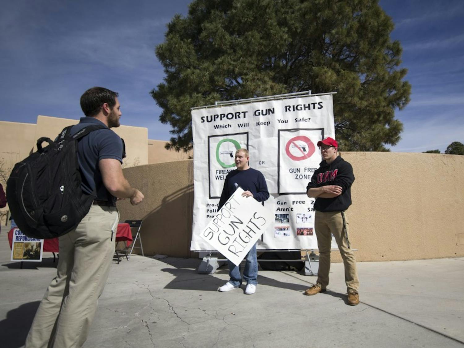 Ryan Boyle and Josh Cde Baca, members of the UNM Young Americans for Freedom group, speak with a student about gun rights on Thursday. UNM Young Americans for Freedom rallied outside of Zimmerman Library while offering flyers that included gun facts and plastic squirt guns.