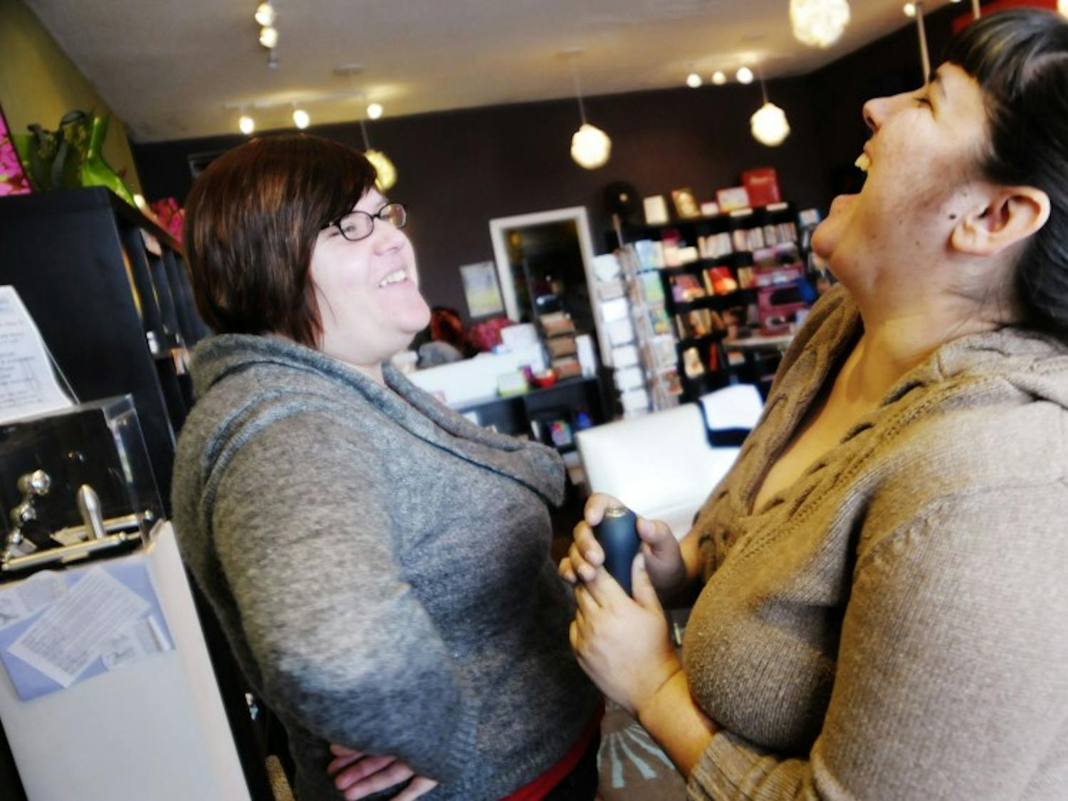 	From left, Matie Fricker, co-owner of Self Serve, shows Aimee Thompson on Monday how a rechargeable vibrator works. Self Serve offers their customers 18 possible discounts, including military, student and senior.