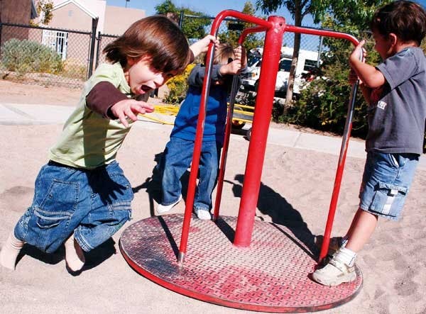 Lucas Gerding, left, spins Aiden Mabry, center, and Daniel Zandenbergen on the merry-go-round Wednesday at the UNM Children's Campus.
