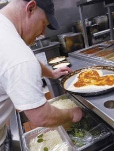Boston's chef Dennis Tugwell prepares a heart-shaped pizza Wednesday on 4300 The 25 Way N.E. For every pizza sold, the national chain of restaurants gives $1 to the Children's Miracle Network.