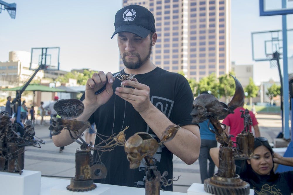 Stephan Webb, a local artist, works on his artwork at 505 Creative Festival at Civic Plaza on Saturday evening. Civic Plaza organized an event that promotes local businesses, organizations and gave an alternative for families and friends to spend their weekend together. 