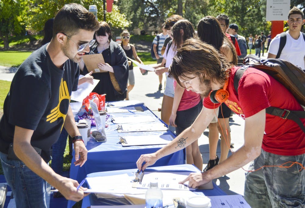 Scott Tillman, left, shows UNM sophomore Sean Cobb, right, the vote pledges to sign Tuesday afternoon for the campaign held near the Duck Pond to decriminalize marijuana in Bernalillo County. DecrimNM will be on campus today and tomorrow.