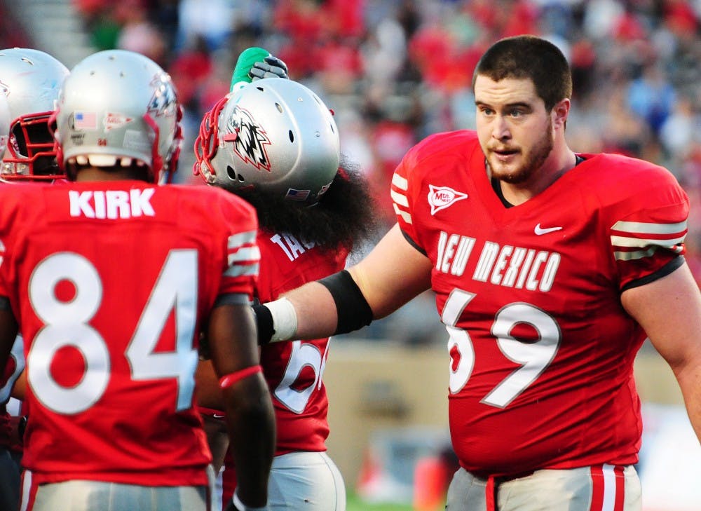 	Former Lobo center Erik Cook walks toward wide receiver Ty Kirk. Cook was taken by the Washington Redskins in the seventh round of the NFL Draft。