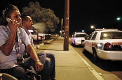 UNM employees Julia Lasky and Jerrett Fleming wait on University Boulevard near UNM Parking and Transportation after being told to stay there by Albuquerque Police officers. Lasky and Fleming were not allowed to go home or  work until the police finished 