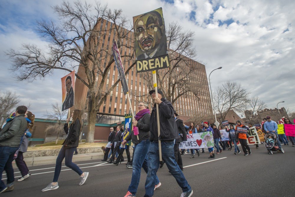 Lonnie Anderson and his family march down Martin Luther King Avenue with hand-painted signs on Saturday, Jan. 14, 2017. Hundreds rallied at UNM and marched down to Albuquerque's Civic Plaza.