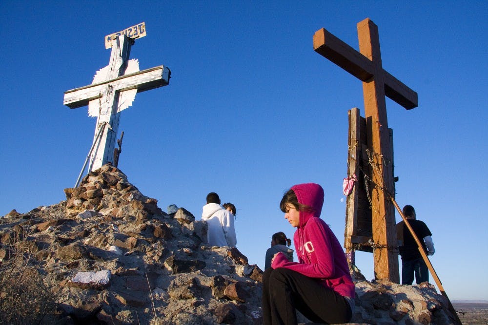 	A young woman shivers and prays at the peak of Tome Hill. Hundreds travelled many miles by foot Friday morning for Good Friday.