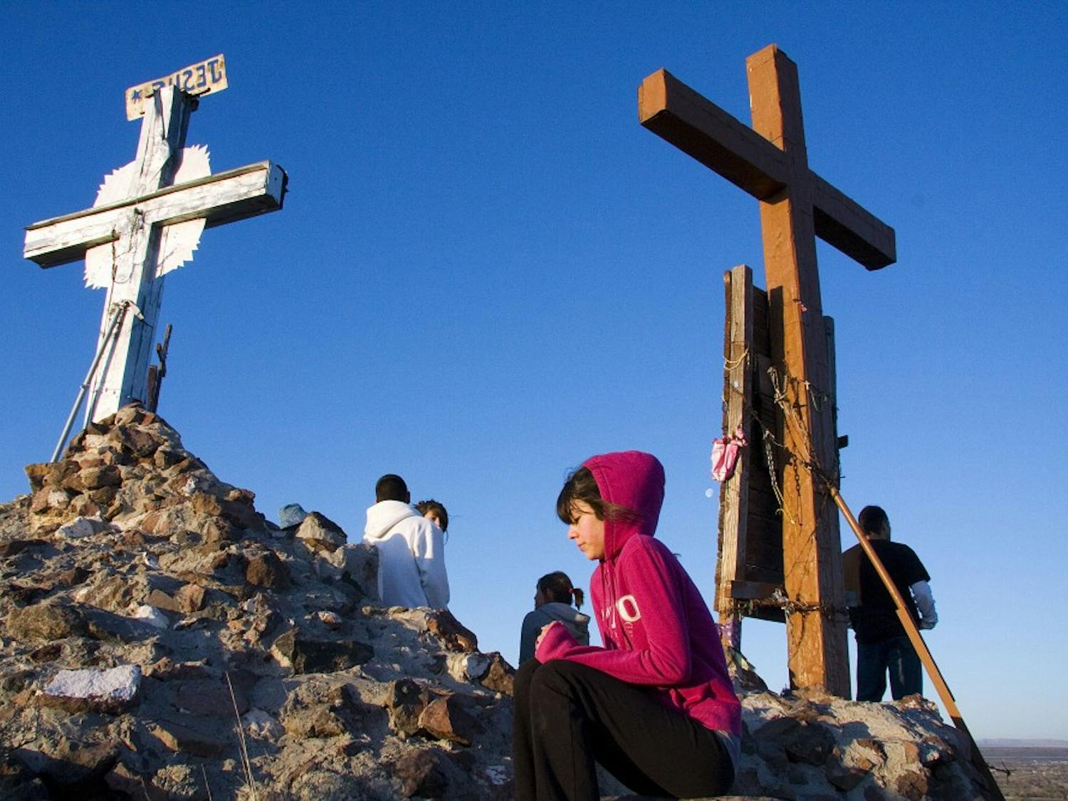 A young woman shivers and prays at the peak of Tome Hill. Hundreds travelled many miles by foot Friday morning for Good Friday.