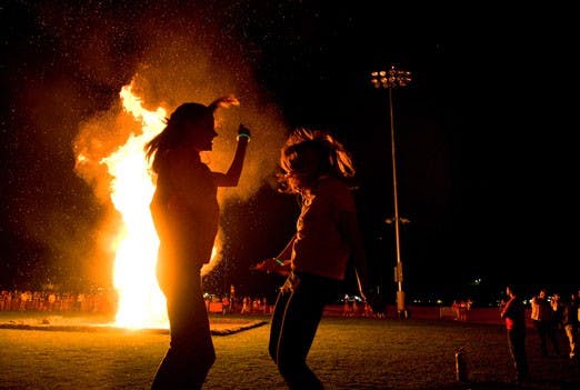 Brianna Duncan and Riana Halstead dance at Red Rally on Thursday. About 300 people turned out at Johnson Field to burn an Aggie effigy and promote Saturday's game against NMSU. 