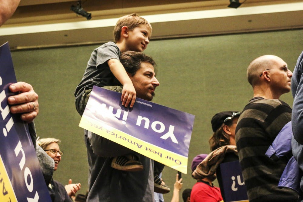 Joshua Oster-Morris and his six-year-old son, Zev Oster, watch Libertarian presidential hopeful Gary Johnson deliver his speech at the UNM SUB ballroom on Saturday, Oct. 8, 2016.