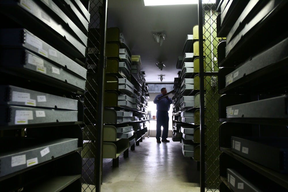 	A worker stocks microfilm on shelves.  The university received a large-sum grant to aid with digitizing and archiving old New Mexican newspapers.  