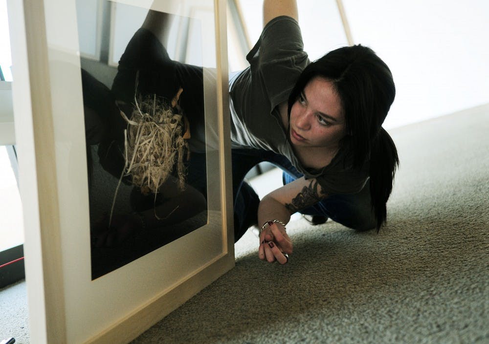 	Artist Lauren Carvalho inspects her work on Sunday at the John Sommers Gallery. She’s having a show there Friday evening.