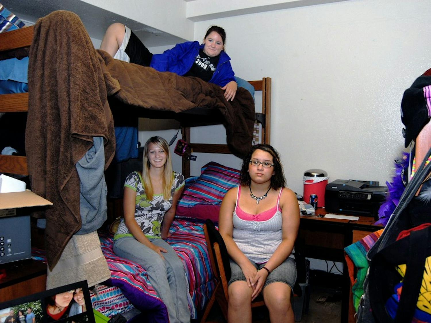 Roommates Alana Meyer, left, Marisa Mapp, top, and Nicole A. Grimaldo hang out in their triple dorm in Coronado Hall on Tuesday. This is the first time the triple-dorm contingency plan has been implemented.