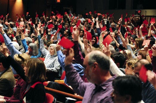 Faculty members use red cards in a "hand vote" on a motion during their meeting on Wednesday at Popejoy Hall. 
