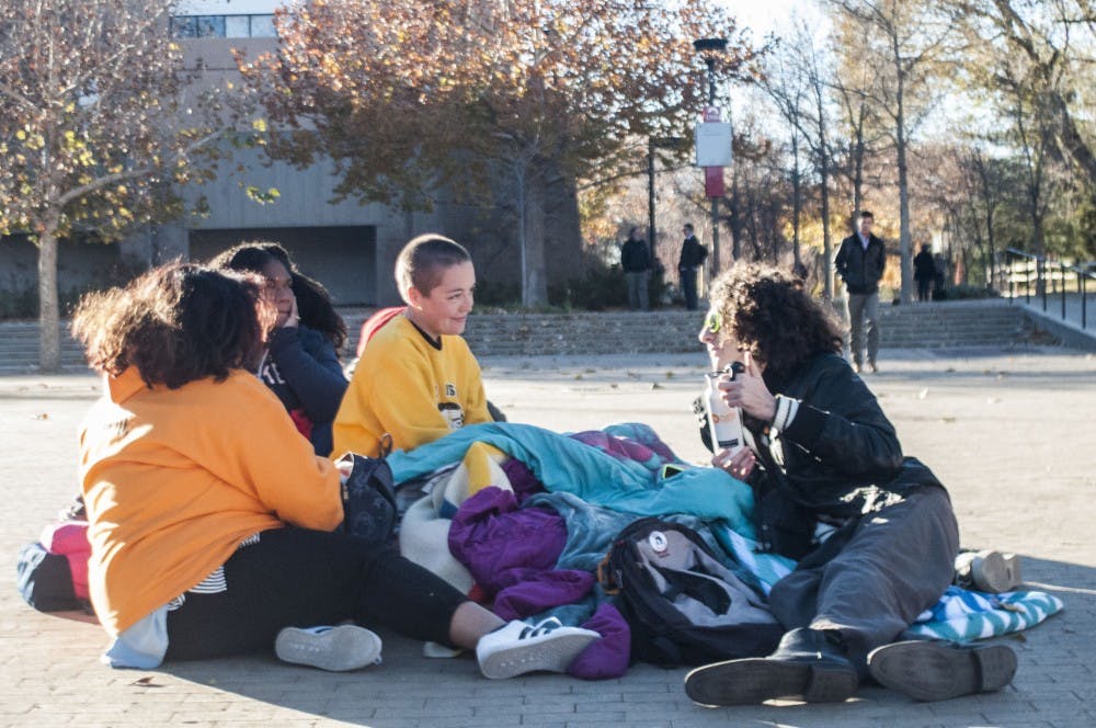 Grace Moreau (center) talks to a peer who stopped by her performance art piece in Smith Plaza on Wednesday, Nov. 30, 2016. Moreau was in Smith Plaza from virtually dawn till dusk, inviting passers-by to the bed as a place of comfort and inclusion.