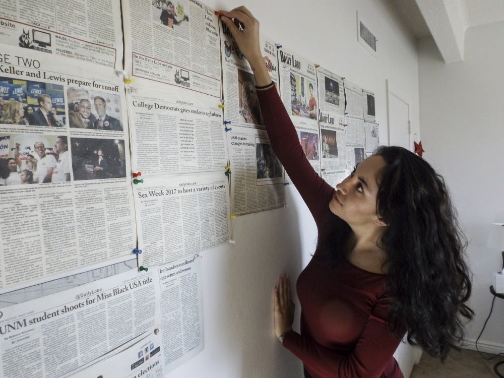 Rebecca Brusseau pins an article to a wall at her apartment on Feb. 3, 2018. This wall houses a collection of articles that she and others have written at the Daily Lobo that she admires.  