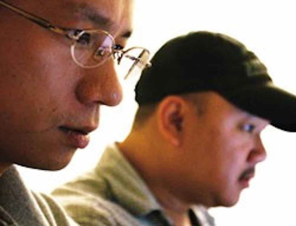 NEC network engineer Maakazu Matsuura, left, and UNM network engineer Benson Nguyen work in a small room connected to the main network switch Monday. "Having Matsuura on hand during the transition is great," said Mark Reynolds, operations manager for tele