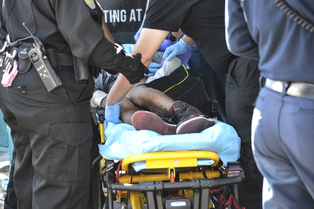 A homeless man is attended to by emergency response providers at a bus stop near the corner of Central Avenue and Yale Boulevard on Thursday. The Central United Methodist Church holds a service every Sunday called Community of Hope, which aims to break through the stigma and generalization set upon a majority of the homeless population.