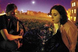 Students Simon Blair, left, and Liz Boyle sit on Johnson Field and smoke strawberry-flavored tobacco out of a hookah Tuesday night.