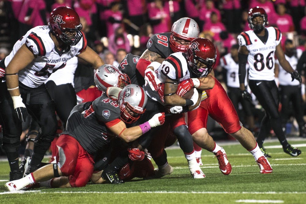 Three New Mexico defensive linemen tackle San Diego State running back Donnel Pumphrey during the Oct. 10 game. The Lobos, who have struggled to win Mountain West games in recent years, resumes conference play Saturday at UNLV.