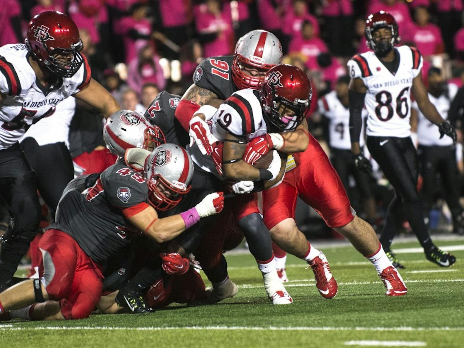 Three New Mexico defensive linemen tackle San Diego State running back Donnel Pumphrey during the Oct. 10 game. The Lobos, who have struggled to win Mountain West games in recent years, resumes conference play Saturday at UNLV.