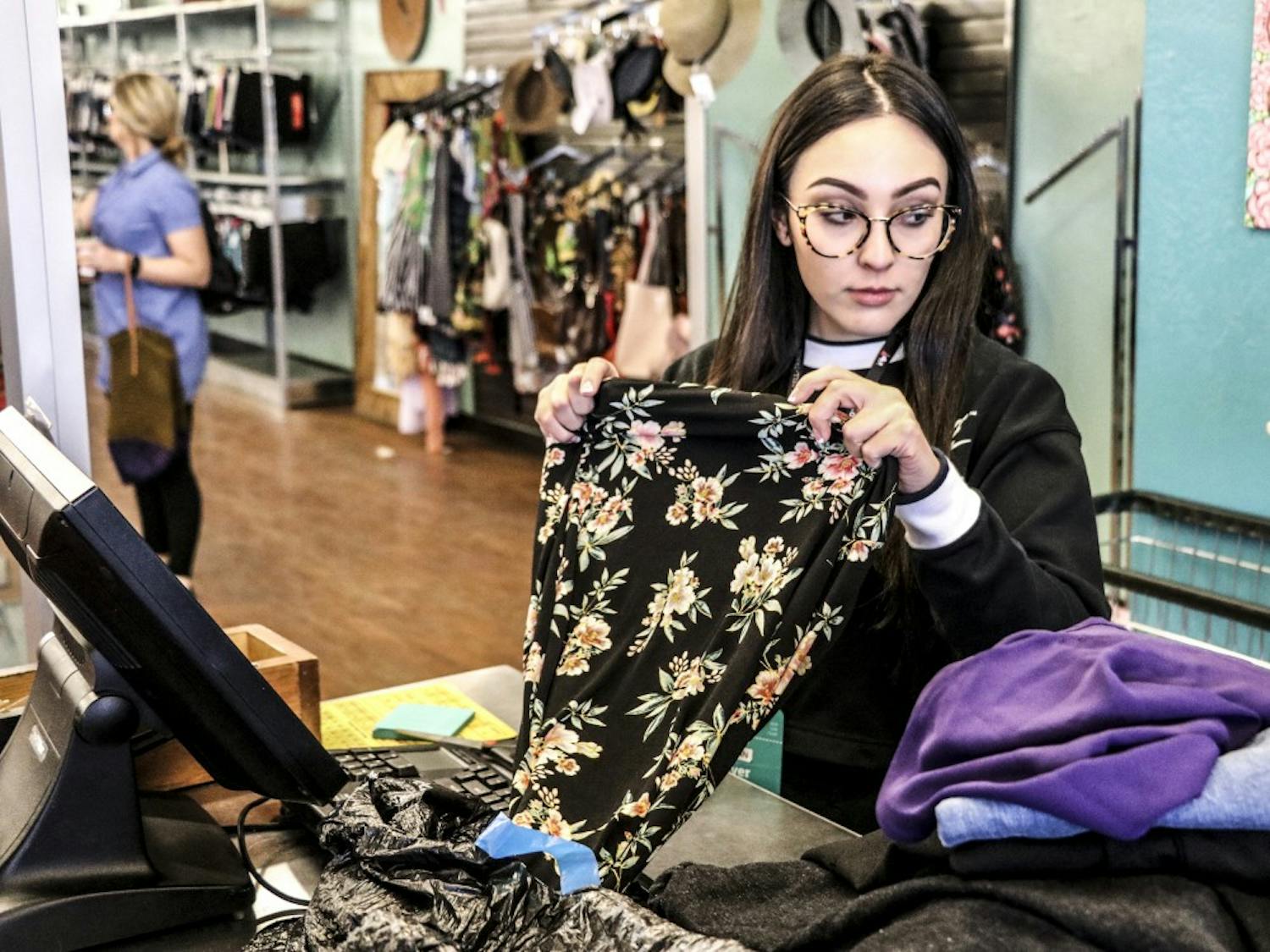 A Buffalo Exchange employee picks through clothes that were dropped off and decides whether or not to buy them for resale on April, 18, 2018. 