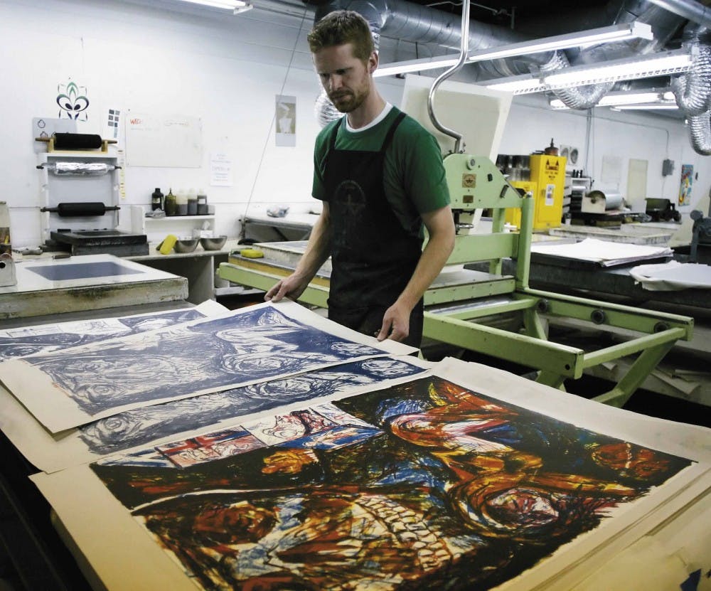 Student Brandon Gunn looks at one his prints before adding color to it. 