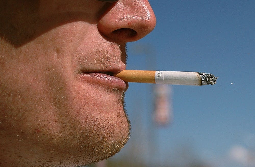 	Student Brandon Whitney takes a long drag on a cigarette near a designated smoking area on campus. The New Mexico Legislature approved a75-cent tax on cigarettes at its last specialsession.