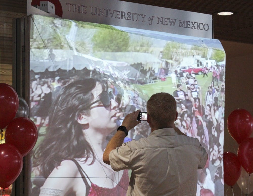 An arriving passenger takes a picture at the unveiling of the UNM LoboScape Monday morning at the Albuquerque International Sunport. The LoboScape is an art display that shows the history of UNM and aims to inform visitors of Albuquerques college town affluence. 