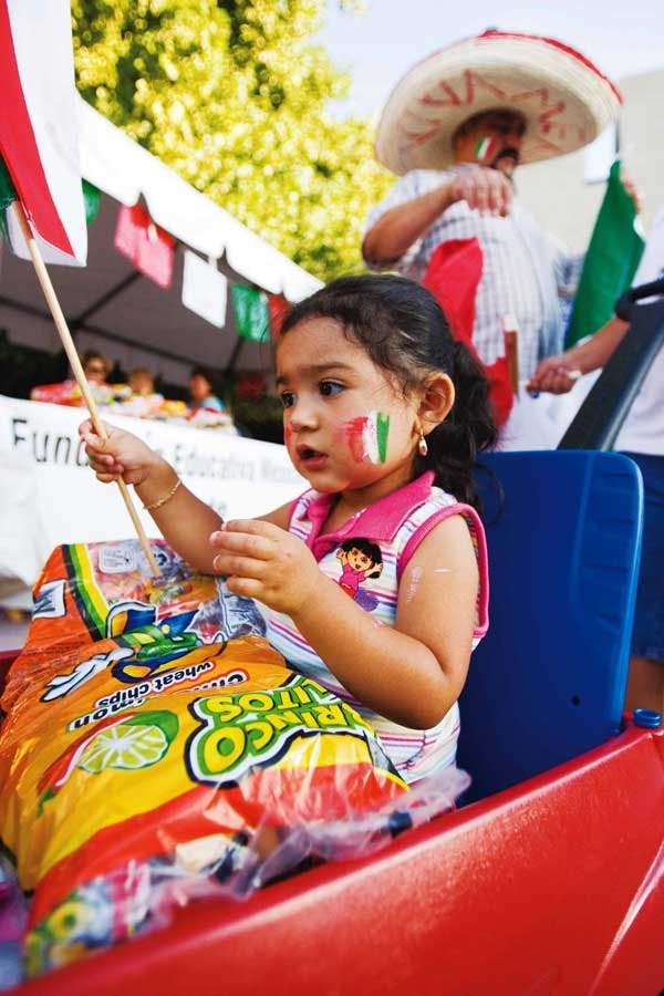 Brenda Martinez plays with a Mexican flag while her father, Sergio, folds a flag at the National Hispanic Cultural Center on Sunday. 