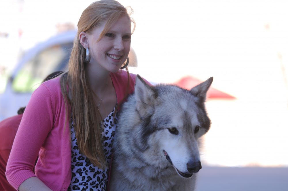 UNM student Devon Rosenkoetter poses with a wolf from the Wanagi Wolf Fund and Rescue at Smith Plaza last Friday. Only 58 Mexican gray wolves survive in the wild in the state, but the UNM Wilderness Alliance and Biology Undergraduate Society are trying to get the community involved in protecting the endangered species.
