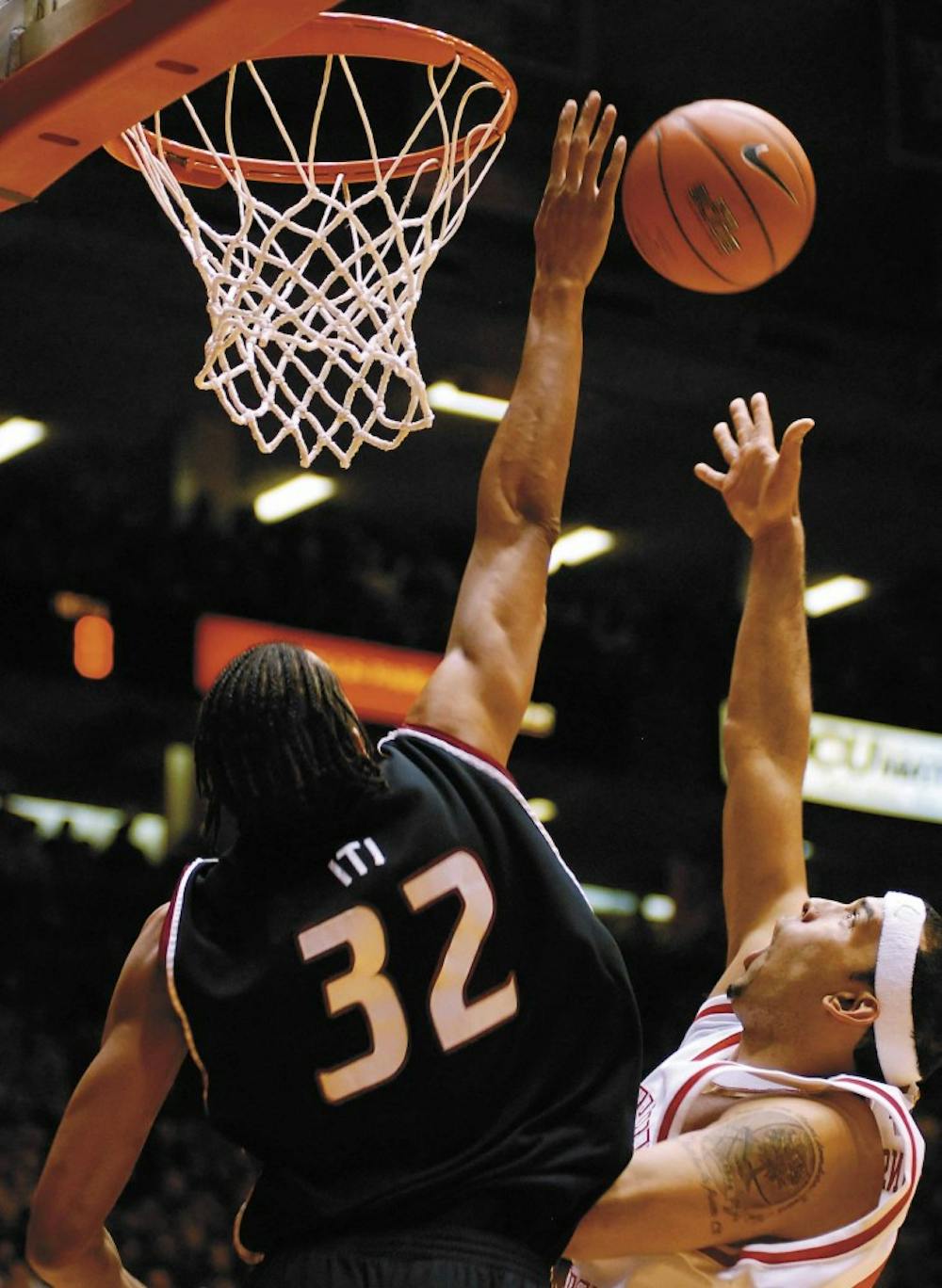 UNM forward Aaron Johnson's shot is blocked by NMSU center Martin Iti in the closing minutes of the Lobo's three-point victory Tuesday at The Pit.