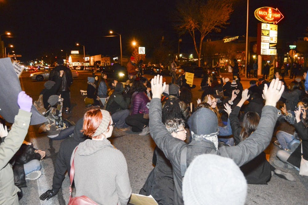 Protesters sit on Central Avenue Tuesday night with their hands up in solidarity with Ferguson, Missouri. The protest took place a day after a Missouri grand jury announced they would not indict Ferguson police officer Darren Wilson in the shooting death of Michael Brown.