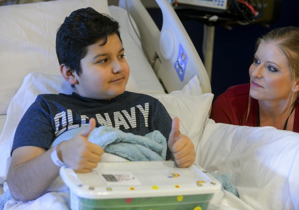 Matthew Castillo, a 12-year-old patient at the UNM Children’s Hospital, reacts to receiving a Jared Box from Kayla Anderson of the District Attorney’s office on Friday, Feb. 5, 2016. DA staff put together care packages full of toys and notes of support and Anderson delivered them.