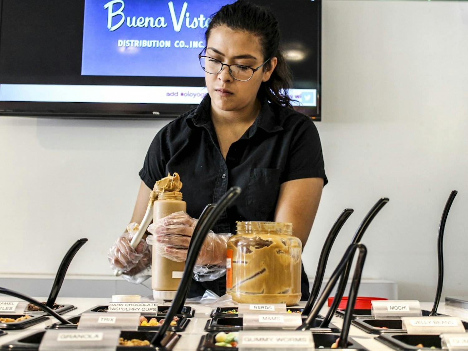 UNM student Sofia Lucero refills flavor toppings Saturday afternoon at Olo Yogurt Studio in Nob Hill. Olo was founded by a UNM alumna. The yogurt studio currently features 10 different flavors and an array of toppings.