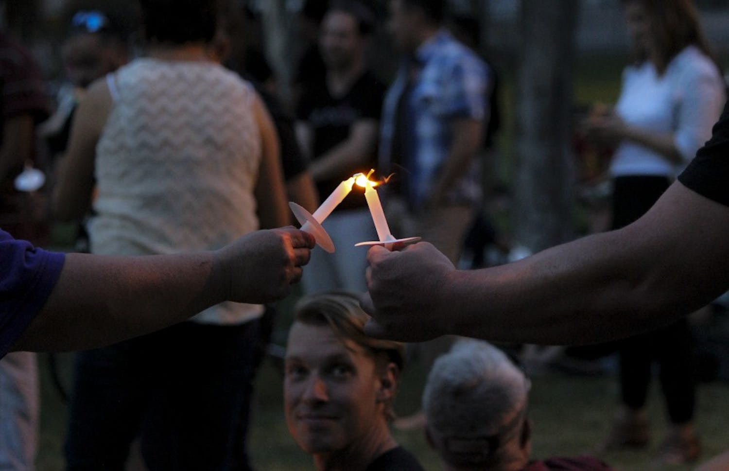 Candlelight Vigil participants light each other's candles as they honor the lives lost within the LGBTQ community at Morningside Park on June 8, 2017. The Candlelight Vigil featured talks from key leaders in the LGBTQ community.
