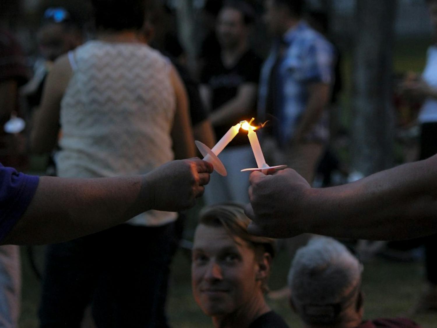 Candlelight Vigil participants light each other's candles as they honor the lives lost within the LGBTQ community at Morningside Park on June 8, 2017. The Candlelight Vigil featured talks from key leaders in the LGBTQ community.