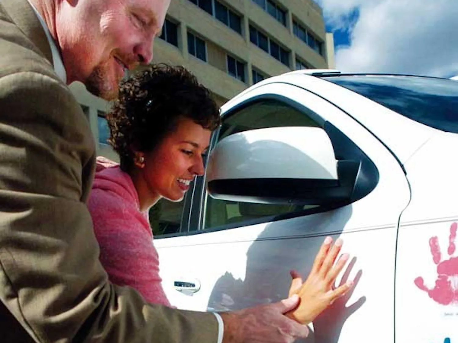 Tom Hornbeck helps Carmen Martinez make a handprint on a Hyundai Santa Fe as part of the Hope on Wheels Tour at the Cancer Research Center on Wednesday. There are six Hyundai vehicles traveling across the country that will be donated to pediatric cancer r
