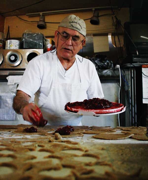 Golden Crown Panaderia owner Pratt Morales puts cherry filling on dough for empanadas Wednesday.