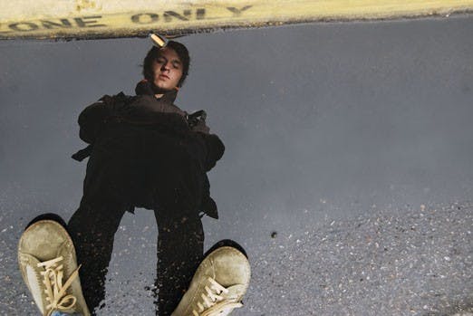 Student Hiram Kamp pauses to look at a puddle on his way to class outside the Communication and Journalism building on Monday. Monday marked the first rainfall this year in Albuquerque.