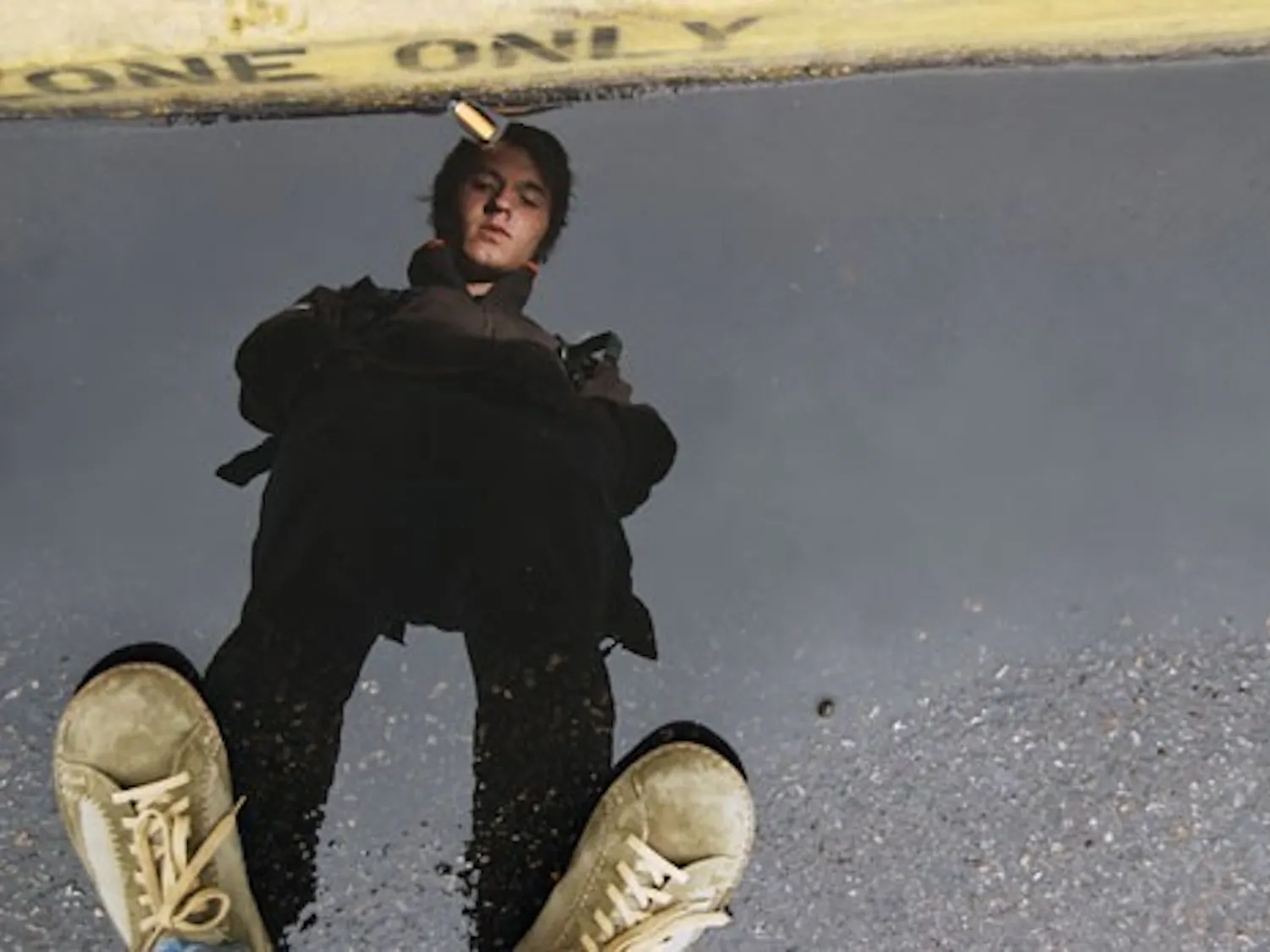 Student Hiram Kamp pauses to look at a puddle on his way to class outside the Communication and Journalism building on Monday. Monday marked the first rainfall this year in Albuquerque.