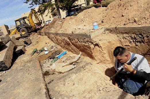 Alfred Lujan fixes a water line near the Center for the Arts building on Monday.