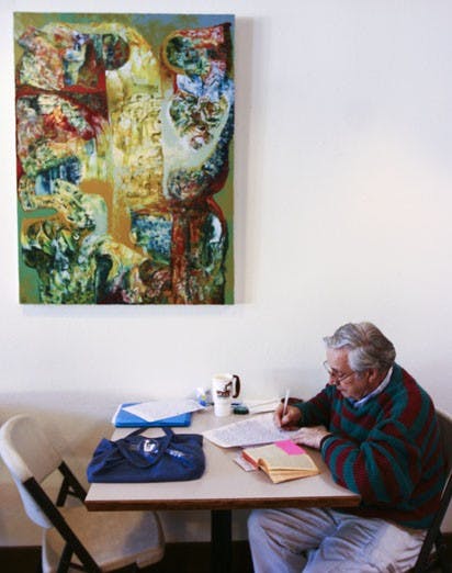 Patrick Policastro reads under a painting by student Jonathan Grimes at Winning Coffee Co. on Monday. Grimes hung his first art show there last week.