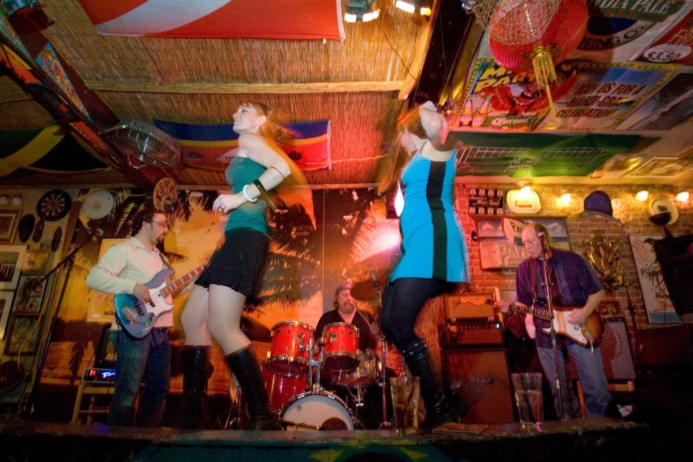 Go-go dancers Amanda Alton, left, and Mica Fraga of the Surf Lords dance while band members Joe Silva, back left, Mike Fleming and Tom Chism perform at Burt's Tiki Lounge on Saturday.