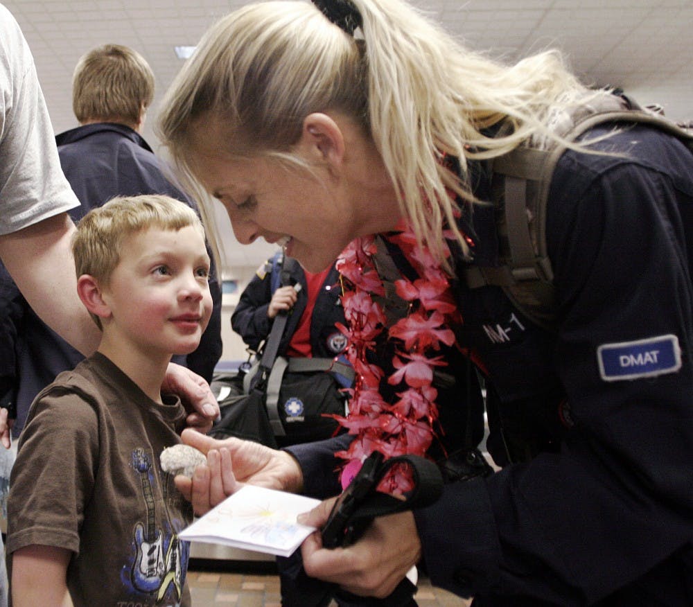 	Christen Naus shows her appreciation for a welcome-back gift from her son, Mason, at the Albuquerque International Sunport on Friday. Naus returned from Haiti with the NM Disaster Medical Assistance Team — which employs the services of six UNM doctors — after two weeks in Port-Au-Prince.