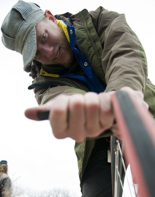Rookie Olson fixes a tire Sunday near the Duck Pond. Olson is a member of Biciaccion, a group of cyclists who help fix bikes on campus.