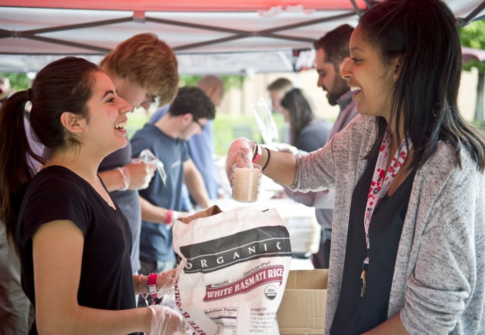 Priscilla Mendoza (left) laughs with Mimmi Muleta while they separate rice in individual bags with other volunteers. Groups of students gathered in front of La Posada to volunteer in a food initiative that was designed to put together bags of rice and beans to give to the Road Runner Food Bank.  