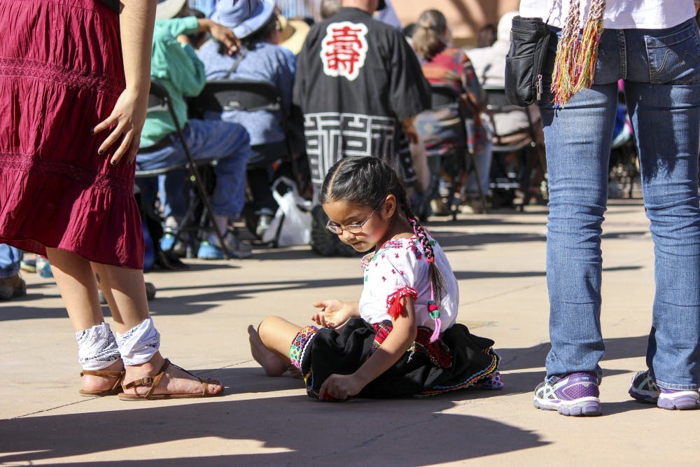 Mari-Fer Straits, age 6, writes on the floor during the anti violence rally on Sunday afternoon at the Civic Plaza. Straits, was one of the four Aztec dance performers from Circulo Solar Ollin Xochipilli that performed at the rally.
