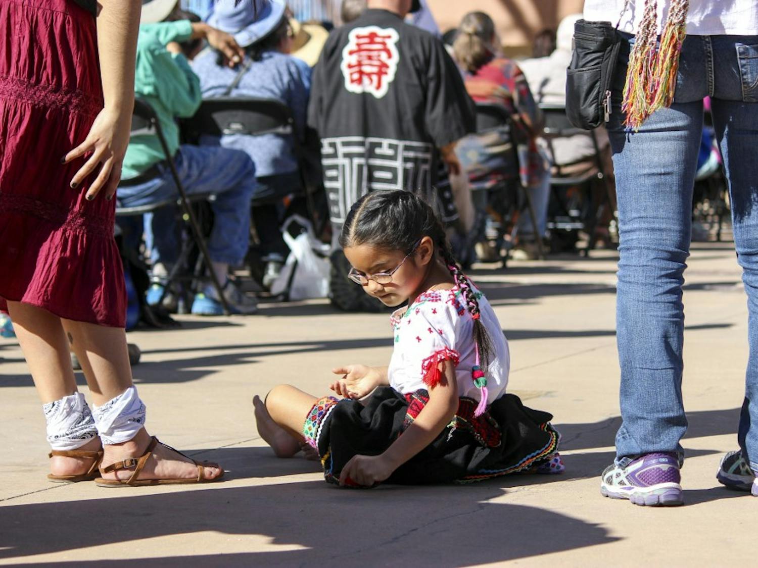 Mari-Fer Straits, age 6, writes on the floor during the anti violence rally on Sunday afternoon at the Civic Plaza. Straits, was one of the four Aztec dance performers from Circulo Solar Ollin Xochipilli that performed at the rally.